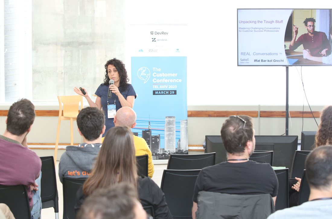 Iffat Bar-Kol Grecht speaking on REAL Conversations at The Customer Conference, in front of a room of managers